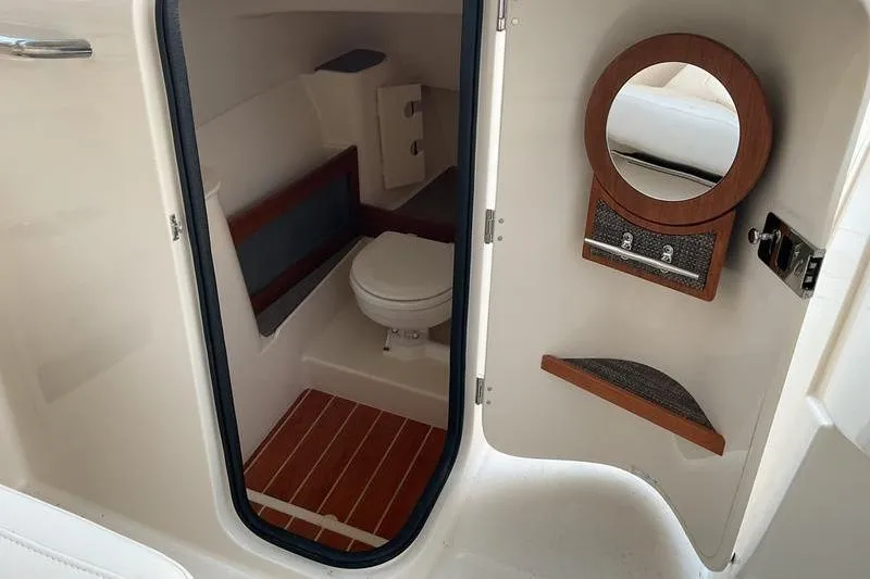 Slide: The Image of 2025 Grady-White Freedom 285 boat interior with compact bathroom and wooden accents. - 11