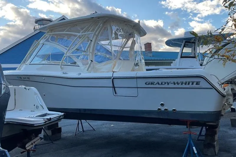 Slide: The Image of 2025 Grady-White Freedom 285 boat on stands, covered, with a blue building background. - 4