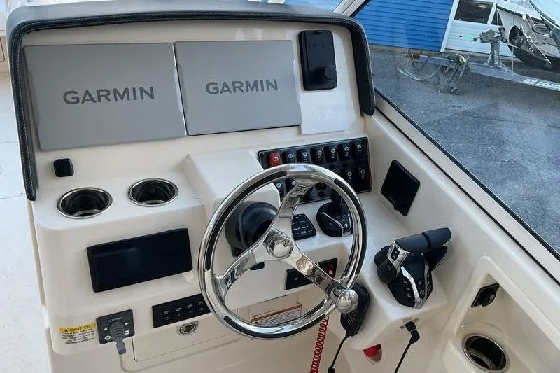 Slide: The Image of 2025 Grady-White Freedom 285 boat dashboard with Garmin navigation systems and steering wheel. - 9