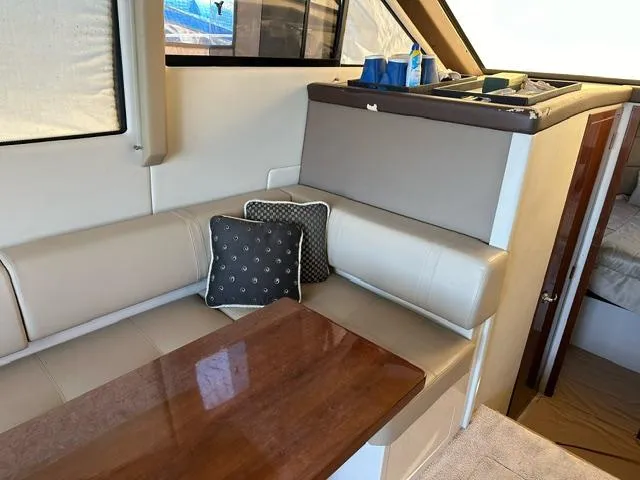 Slide: The Image of Interior of 2016 Carver C34 Command Bridge with beige seating and wooden table. - 16