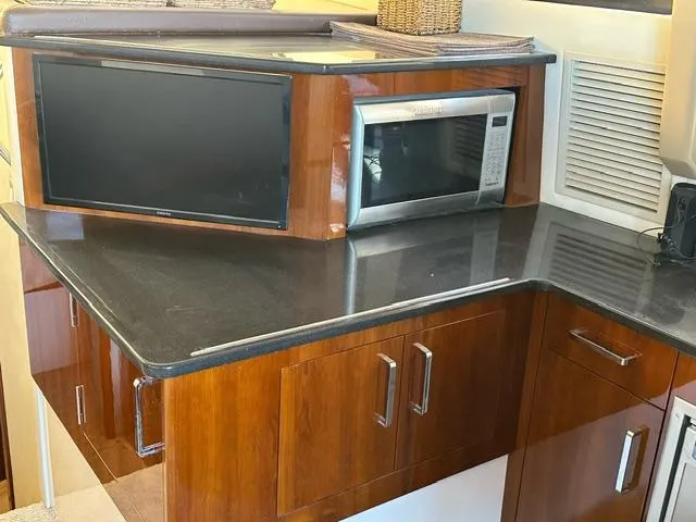 Slide: The Image of 2016 Carver C34 Command Bridge kitchen with microwave and sleek wooden cabinetry. - 18