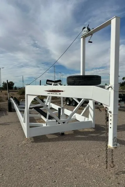 Slide: The Image of White boat trailer for 2016 Carver C34 Command Bridge, parked on gravel under cloudy sky. - 29