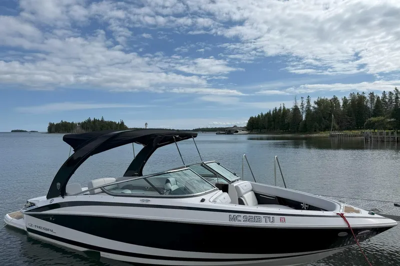 Slide: The Image of 2016 Regal 2500 Bowrider boat docked on a serene lake with forested shoreline. - 3