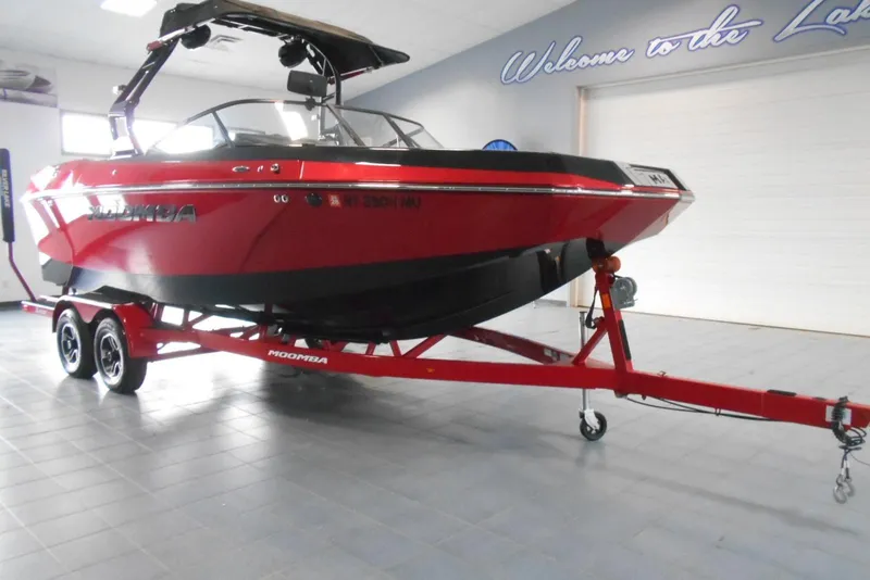 Slide: The Image of 2023 Moomba Max boat in showroom, red and black design on trailer. - 1