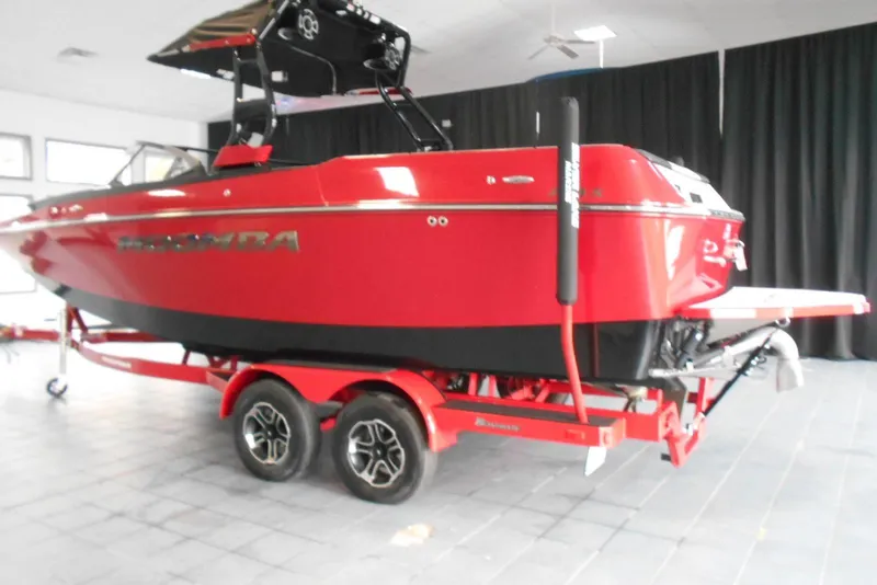 Slide: The Image of 2023 Moomba Max boat in vibrant red on a trailer, displayed indoors. - 4