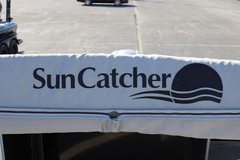 Slide: The Image of 2021 SunCatcher Select 22C boat cover with logo in a parking lot. - 22