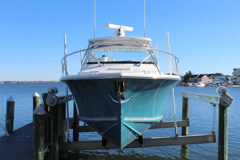 Slide: The Image of 2022 Albemarle 30 Express boat docked on a lift, with a scenic waterfront backdrop. - 10