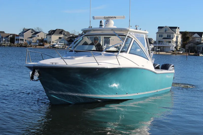 Slide: The Image of 2022 Albemarle 30 Express boat on water, with coastal homes in the background. - 2