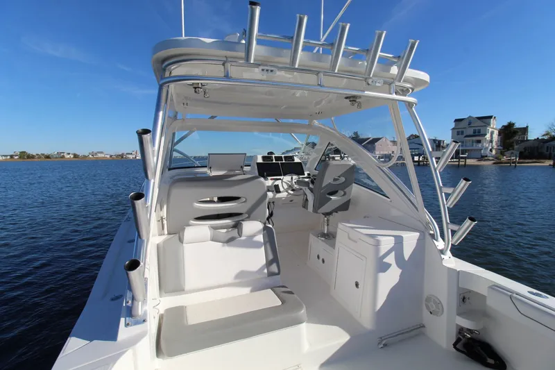 Slide: The Image of 2022 Albemarle 30 Express boat interior with seating and helm, docked on calm water. - 20