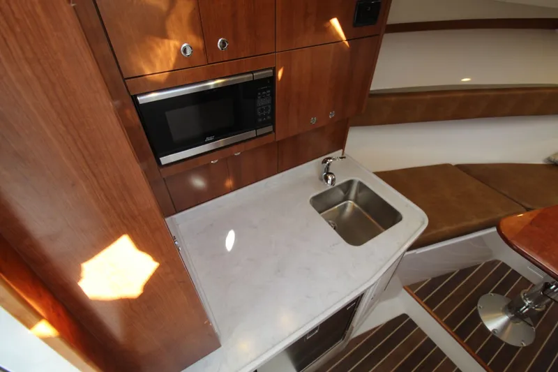Slide: The Image of 2022 Albemarle 30 Express cabin with kitchenette, featuring a microwave, sink, and seating area. - 32