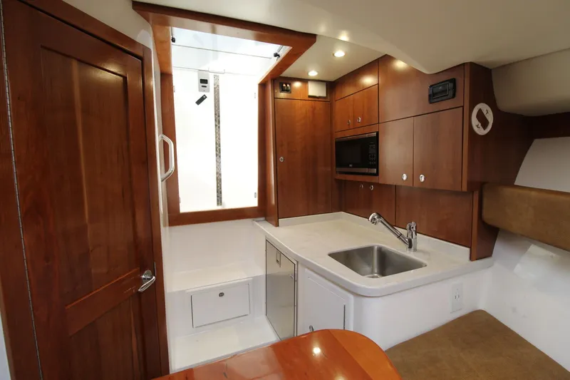 Slide: The Image of 2022 Albemarle 30 Express boat interior with modern kitchenette and wooden cabinetry. - 37