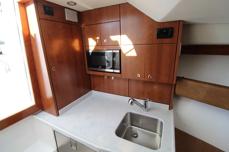 Slide: The Image of 2022 Albemarle 30 Express boat interior with wooden cabinetry and stainless steel sink. - 38