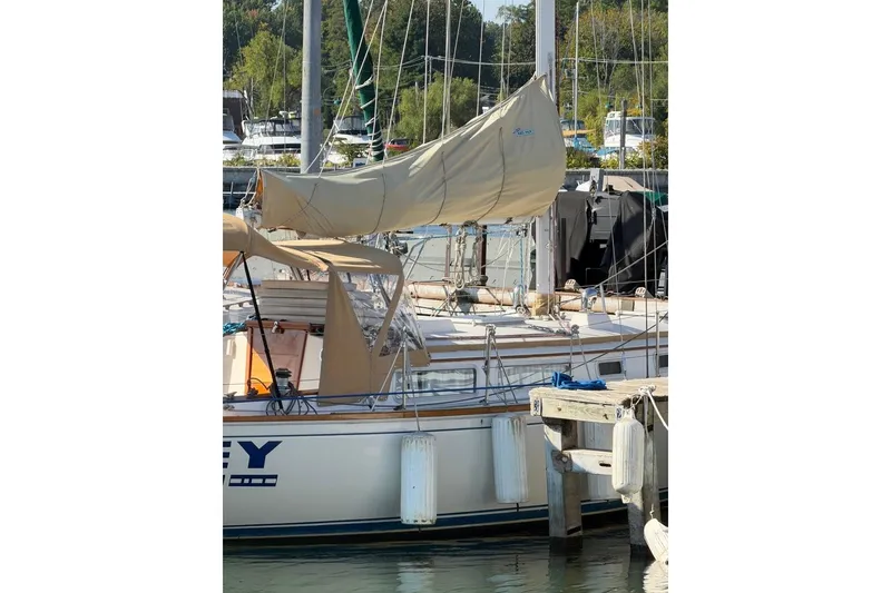 Slide: The Image of 1984 Sabre 34-1 sailboat docked, featuring a beige canopy and ladder. - 17