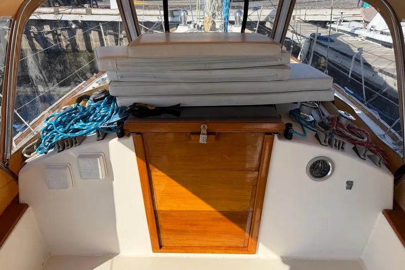 Slide: The Image of 1984 Sabre 34-1 sailboat cockpit with ropes, cushions, and wooden hatch. - 34