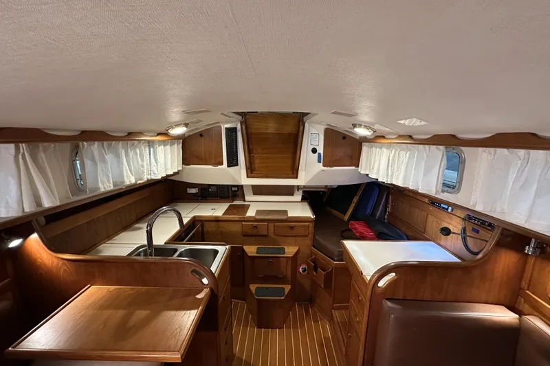 Slide: The Image of 1984 Sabre 34-1 yacht interior with wood finish, kitchenette, and seating area. - 42