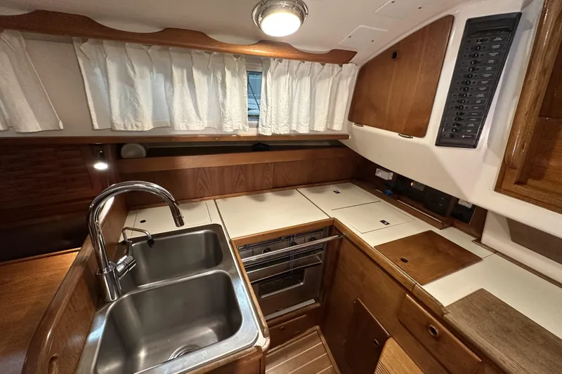 Slide: The Image of 1984 Sabre 34-1 yacht kitchen with dual sink, stove, and wooden cabinetry. - 46