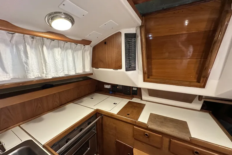 Slide: The Image of 1984 Sabre 34-1 yacht interior kitchen with wood cabinetry and white countertops. - 48