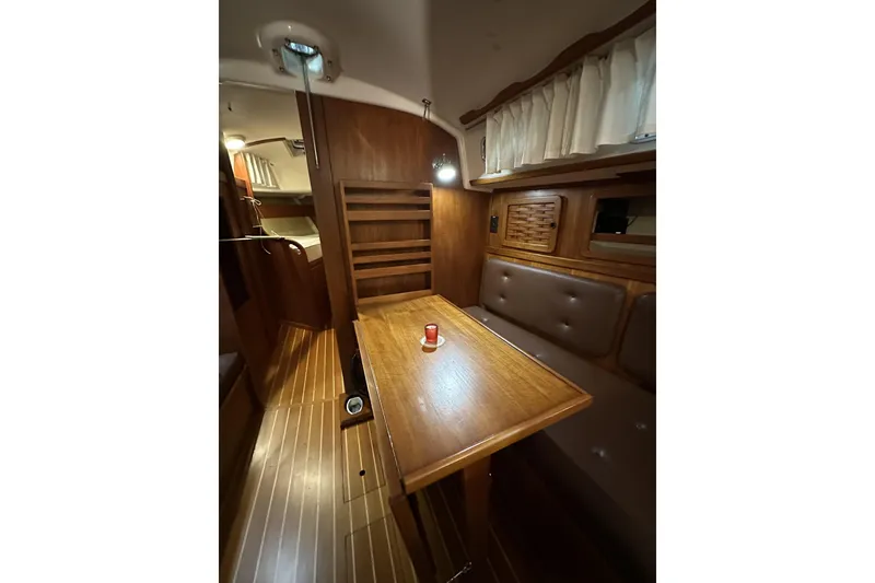 Slide: The Image of 1984 Sabre 34-1 yacht interior with wooden table, cushioned seating, and ambient lighting. - 62