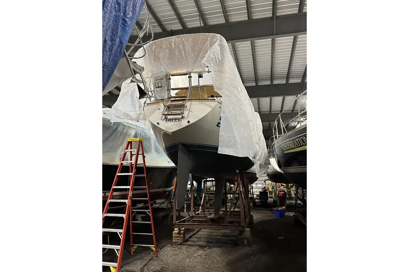 Slide: The Image of 1984 Sabre 34-1 sailboat in storage, covered with tarp, alongside a red ladder. - 72