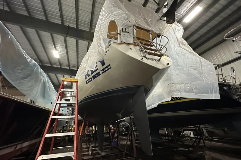 Slide: The Image of 1984 Sabre 34-1 sailboat in indoor storage, partially covered, with a ladder nearby. - 74