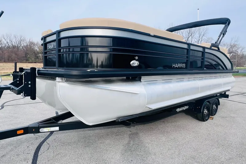 Slide: The Image of 2024 Harris Sunliner 250 pontoon boat on trailer, black and silver design. - 3