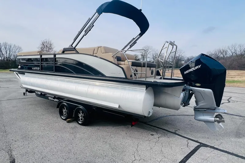 Slide: The Image of 2024 Harris Sunliner 250 pontoon boat with Mercury outboard engine on a trailer. - 4