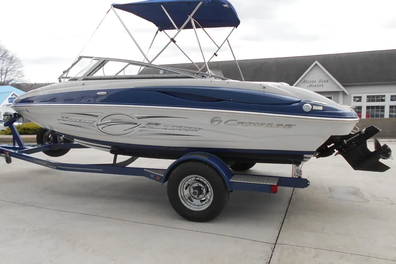 The Image of 2012 Crownline 205 SS boat on trailer with blue canopy, parked outdoors. - 0