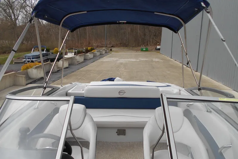 Slide: The Image of 2012 Crownline 205 SS boat with blue canopy, parked outdoors near a building. - 13