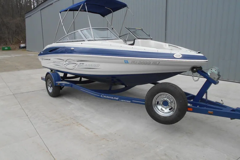 Slide: The Image of 2012 Crownline 205 SS boat on trailer, blue and white design, parked outdoors. - 3