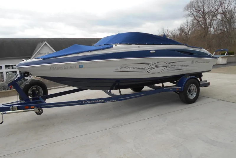 Slide: The Image of 2012 Crownline 205 SS boat on trailer, blue and white design, parked outdoors. - 4