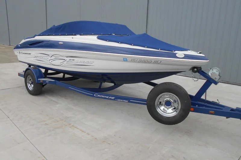 Slide: The Image of 2012 Crownline 205 SS boat on trailer with blue cover, parked on concrete surface. - 8