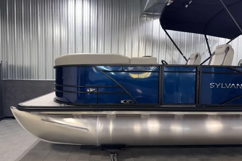 Slide: The Image of 2026 Sylvan Mirage X3 CLZ DH pontoon boat with sleek blue design in a showroom. - 21