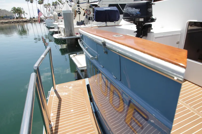 Slide: The Image of 1984 Symbol 51 yacht docked, featuring wooden deck and Tohatsu outboard motor. - 13