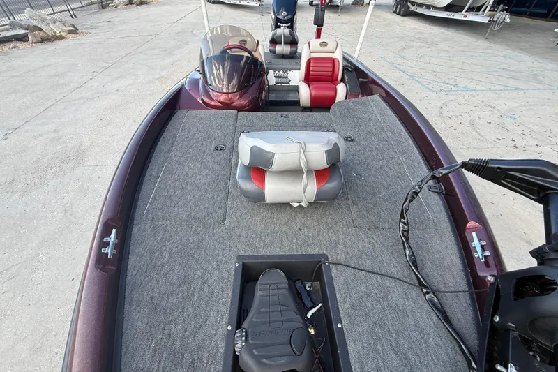 Slide: The Image of 2000 Triton Tr-186 boat interior with seats and steering, parked on concrete. - 11