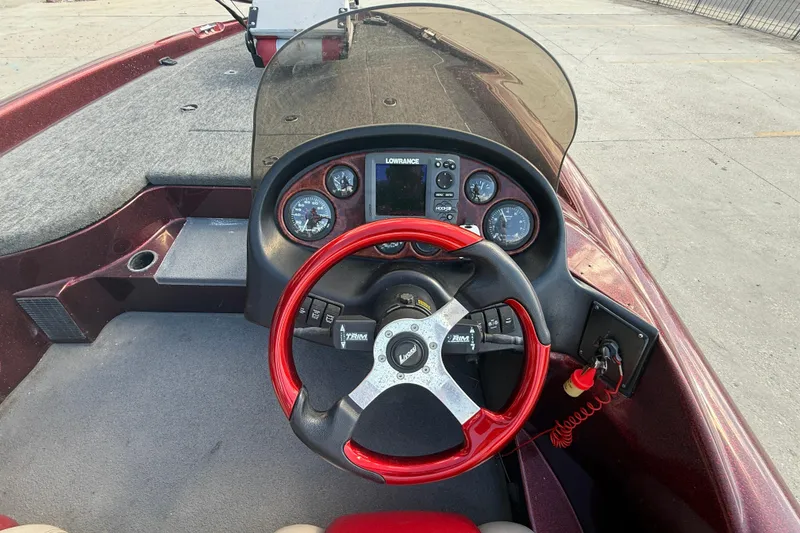 Slide: The Image of 2000 Triton Tr-186 boat dashboard with red steering wheel and navigation instruments. - 15