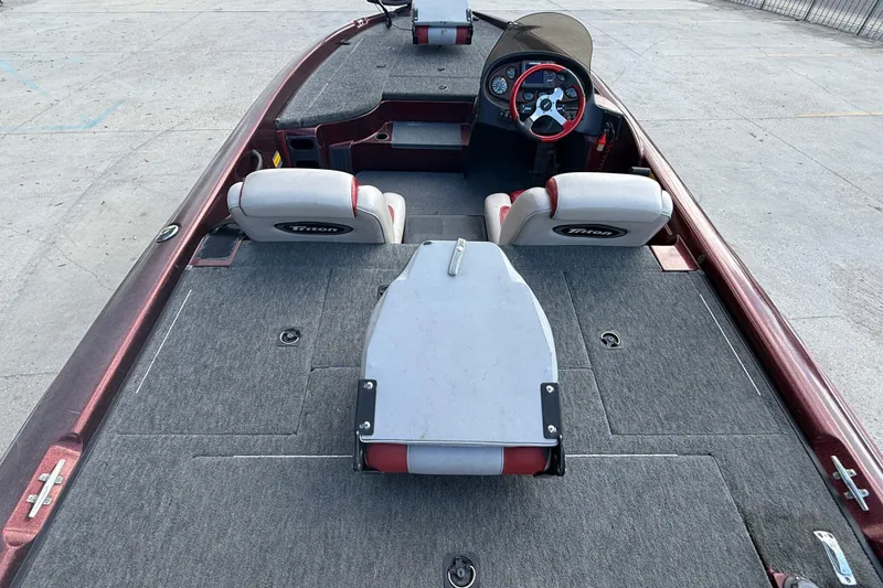 Slide: The Image of 2000 Triton Tr-186 boat interior with steering wheel and seating, featuring gray and red accents. - 8