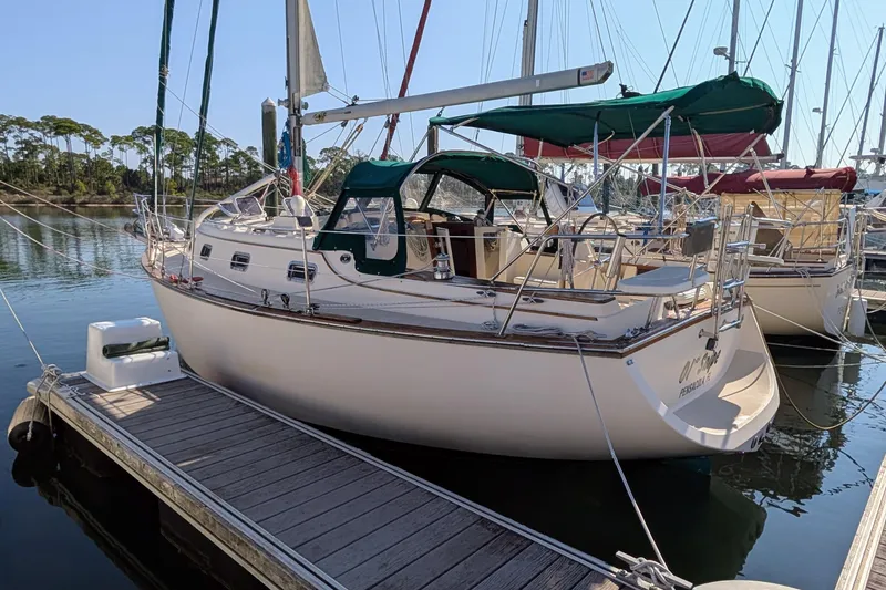 The Image of 1999 Island Packet 320 sailboat docked at marina, featuring green canopy and white hull. - 0