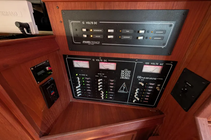 Slide: The Image of Electrical control panel of 1999 Island Packet 320 yacht, featuring 12V DC and 120V AC systems. - 16
