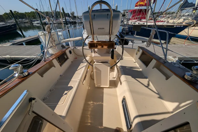 Slide: The Image of 1999 Island Packet 320 sailboat cockpit with steering wheel, docked at marina. - 23