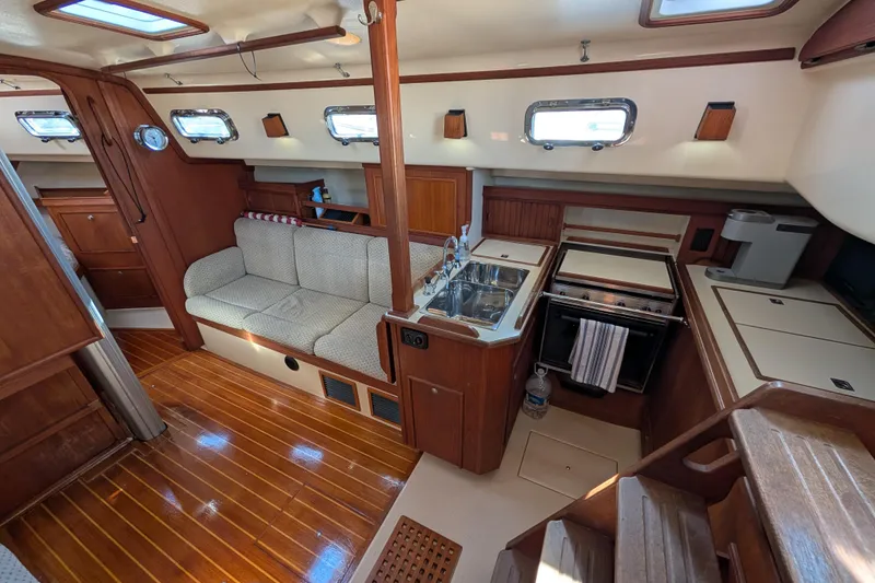 Slide: The Image of Interior of 1999 Island Packet 320 sailboat with cozy seating and compact kitchen area. - 3