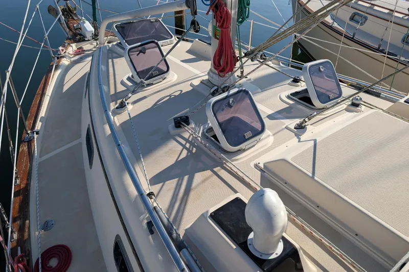 Slide: The Image of 1999 Island Packet 320 sailboat deck with hatches and rigging, docked in calm waters. - 31