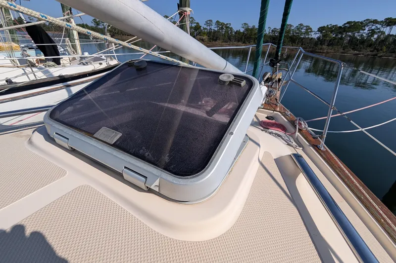 Slide: The Image of 1999 Island Packet 320 sailboat deck with hatch, docked by calm waters. - 34