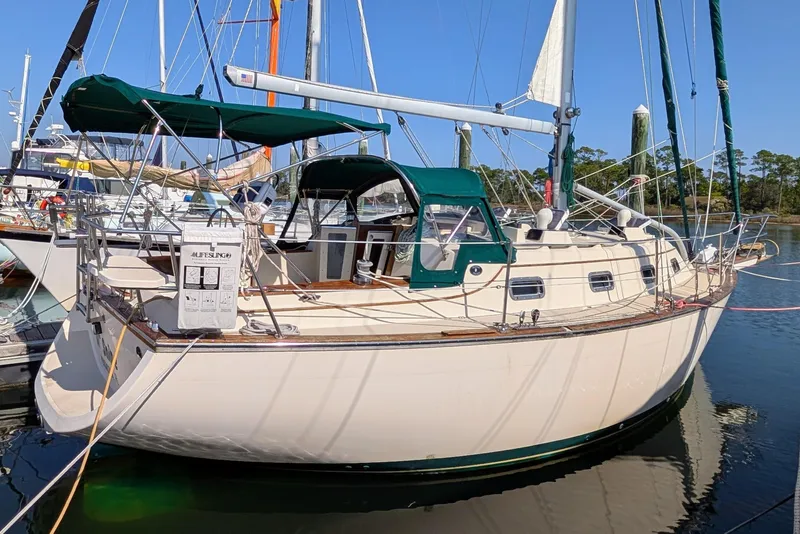 Slide: The Image of 1999 Island Packet 320 sailboat docked in marina, featuring green canopy and classic design. - 40