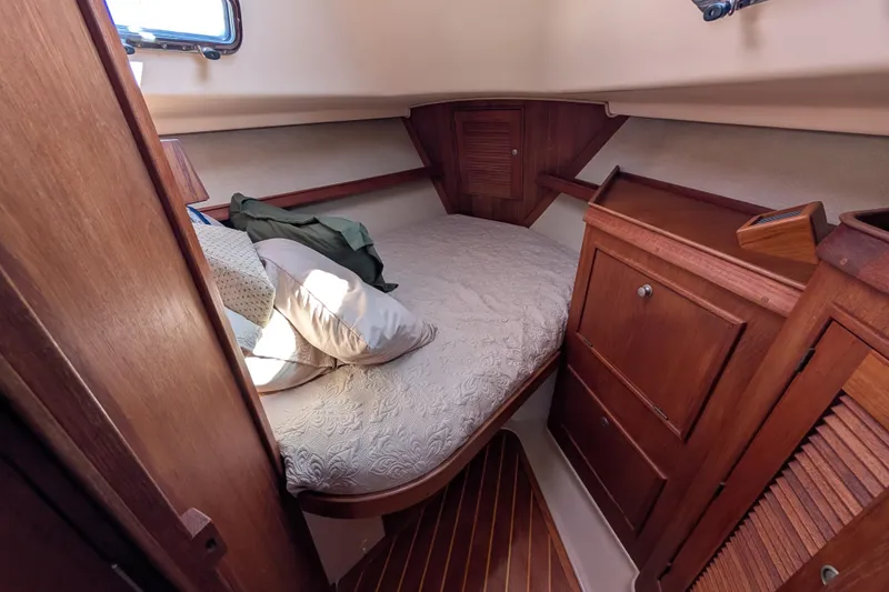Slide: The Image of 1999 Island Packet 320 cabin interior with cozy bed and wooden cabinetry. - 6