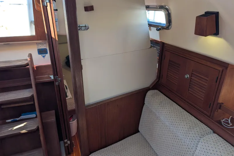 Slide: The Image of Interior of 1999 Island Packet 320 sailboat with wooden cabinetry and cushioned seating. - 9