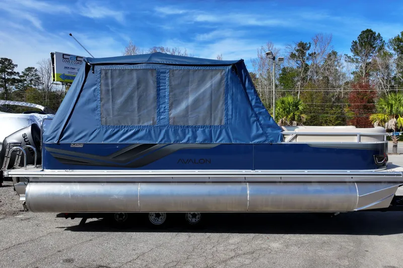 Slide: The Image of 2026 Avalon Venture 85 Rear Fish pontoon boat with blue canopy, parked outdoors. - 2