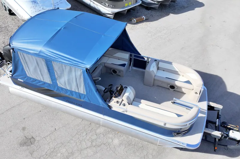 Slide: The Image of 2026 Avalon Venture 85 Rear Fish pontoon boat with blue canopy, docked on a trailer. - 5