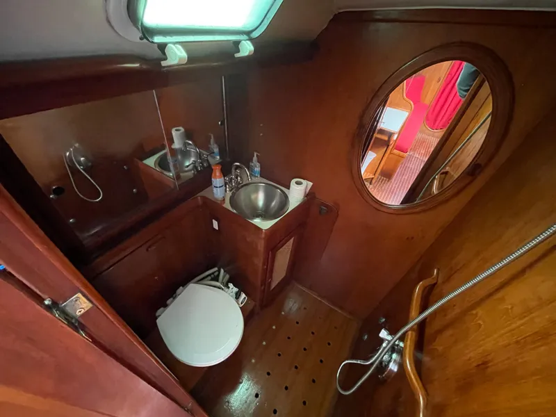 Slide: The Image of 1980 Davidson 44 yacht bathroom with wooden interior and round mirror. - 16