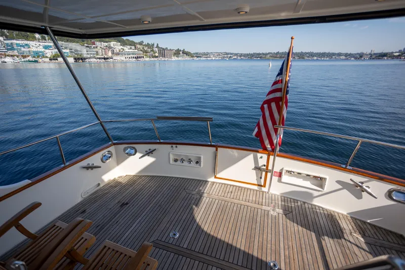 Slide: The Image of Deck view of 2006 Grand Banks 47 Europa yacht with American flag, overlooking serene waters. - 31