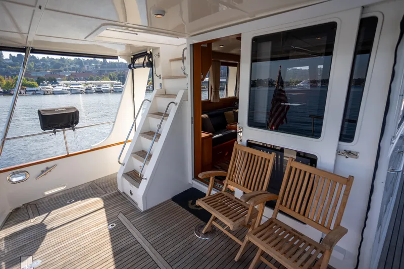 Slide: The Image of 2006 Grand Banks 47 Europa yacht deck with wooden chairs and scenic waterfront view. - 32